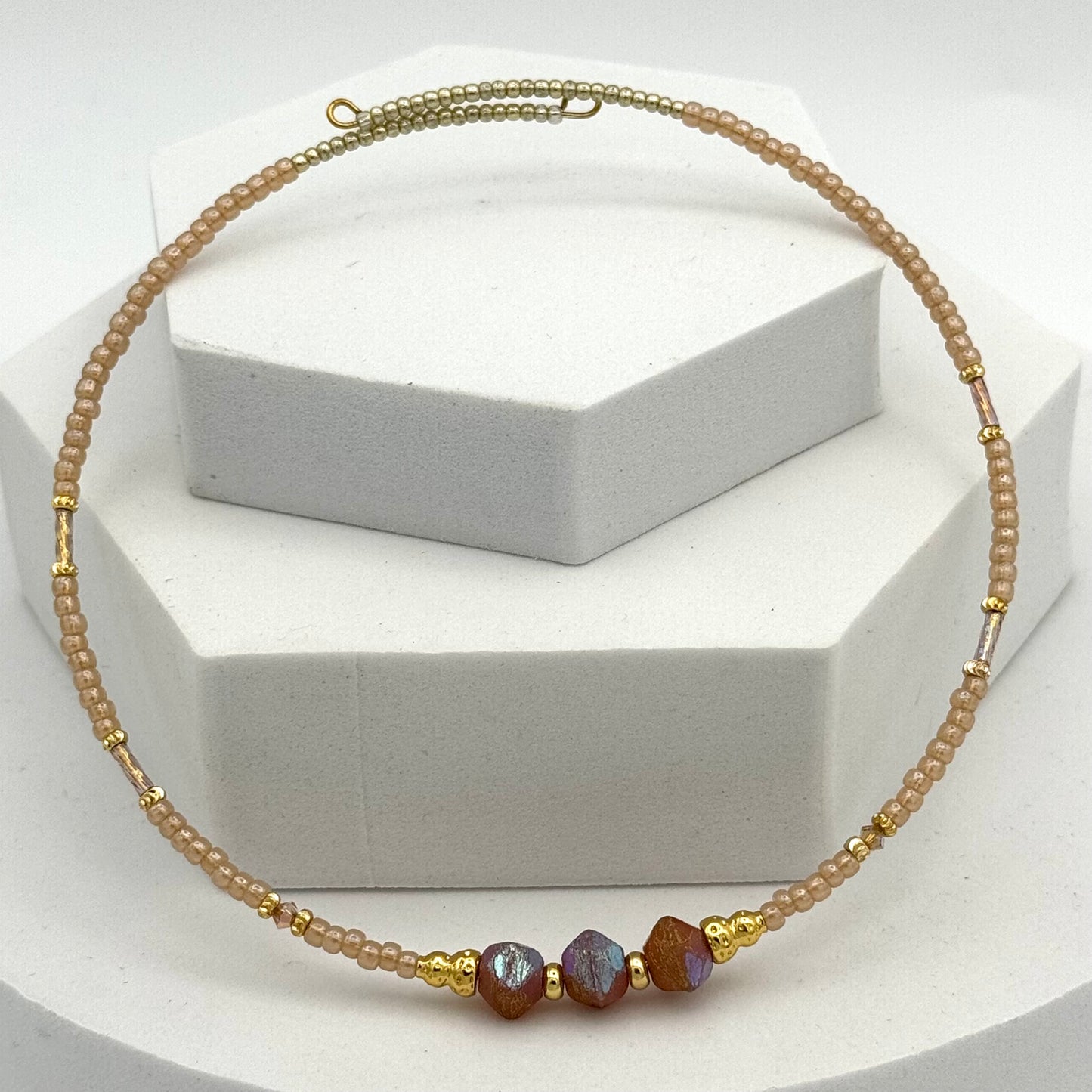 Necklace with gold and brown beads on a white stand