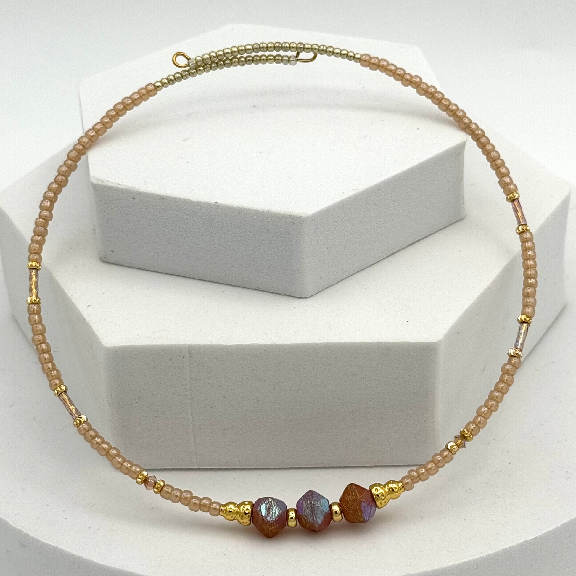 Necklace with gold and brown beads on a white stand
