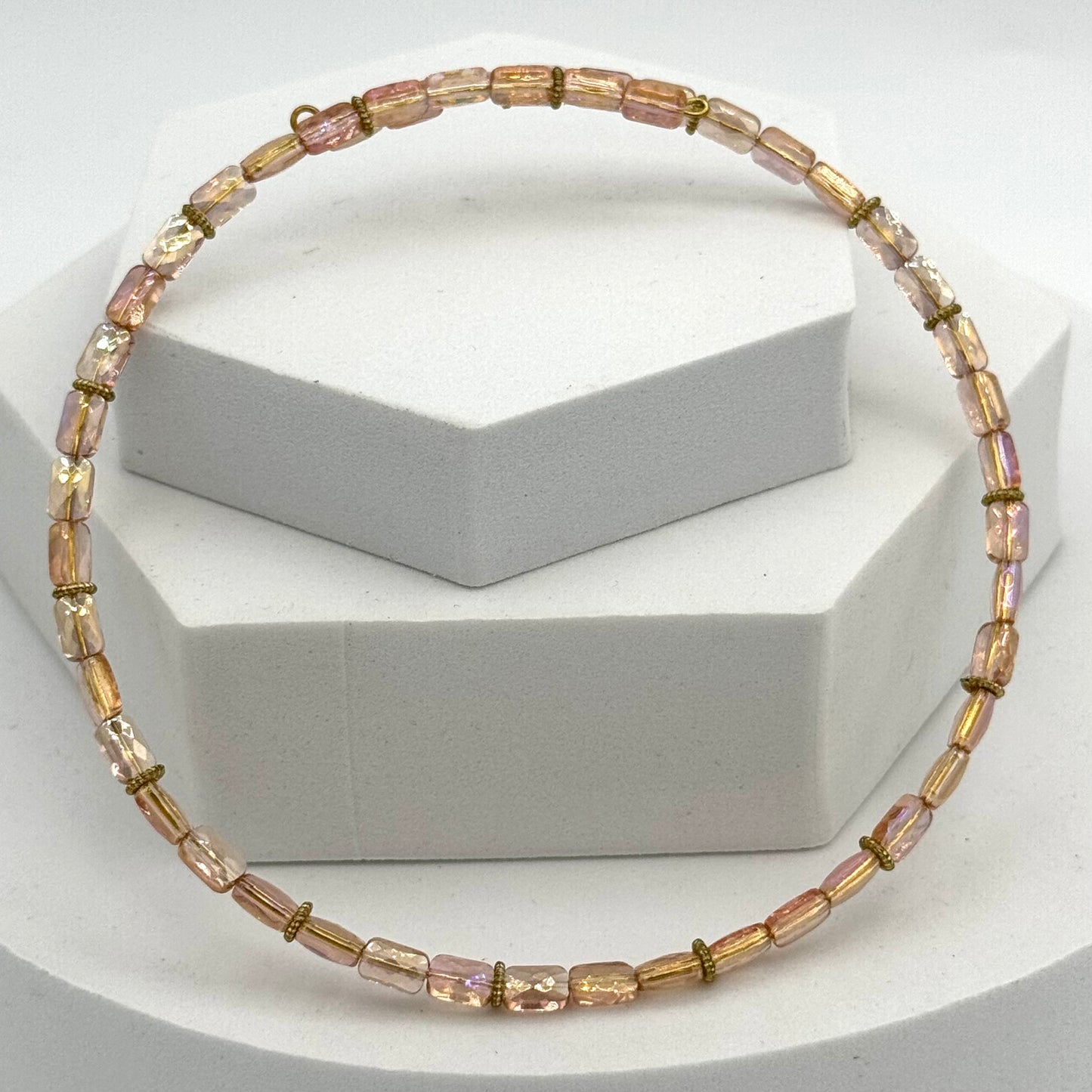 Necklace with pink and gold beads on a white geometric background