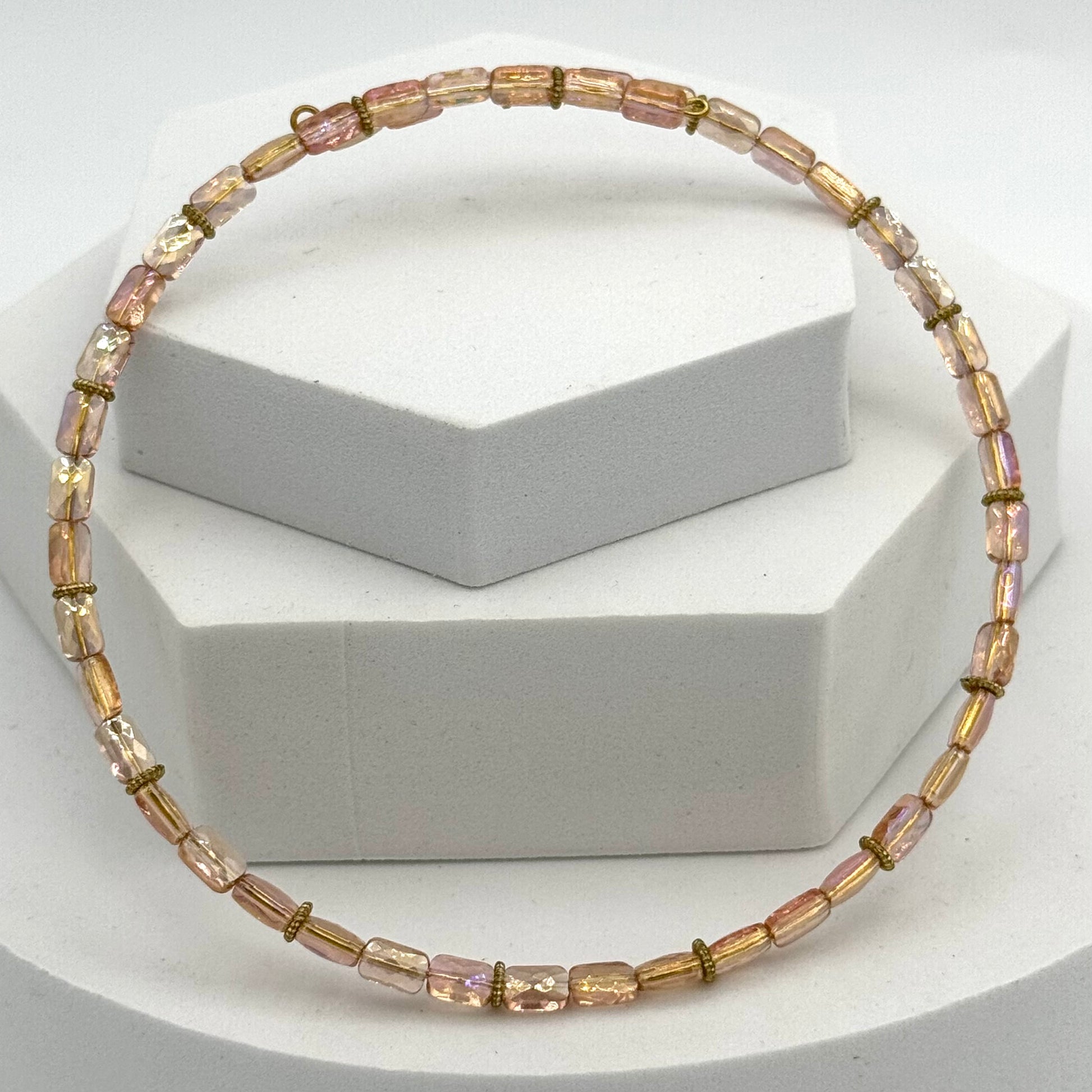 Necklace with pink and gold beads on a white geometric background