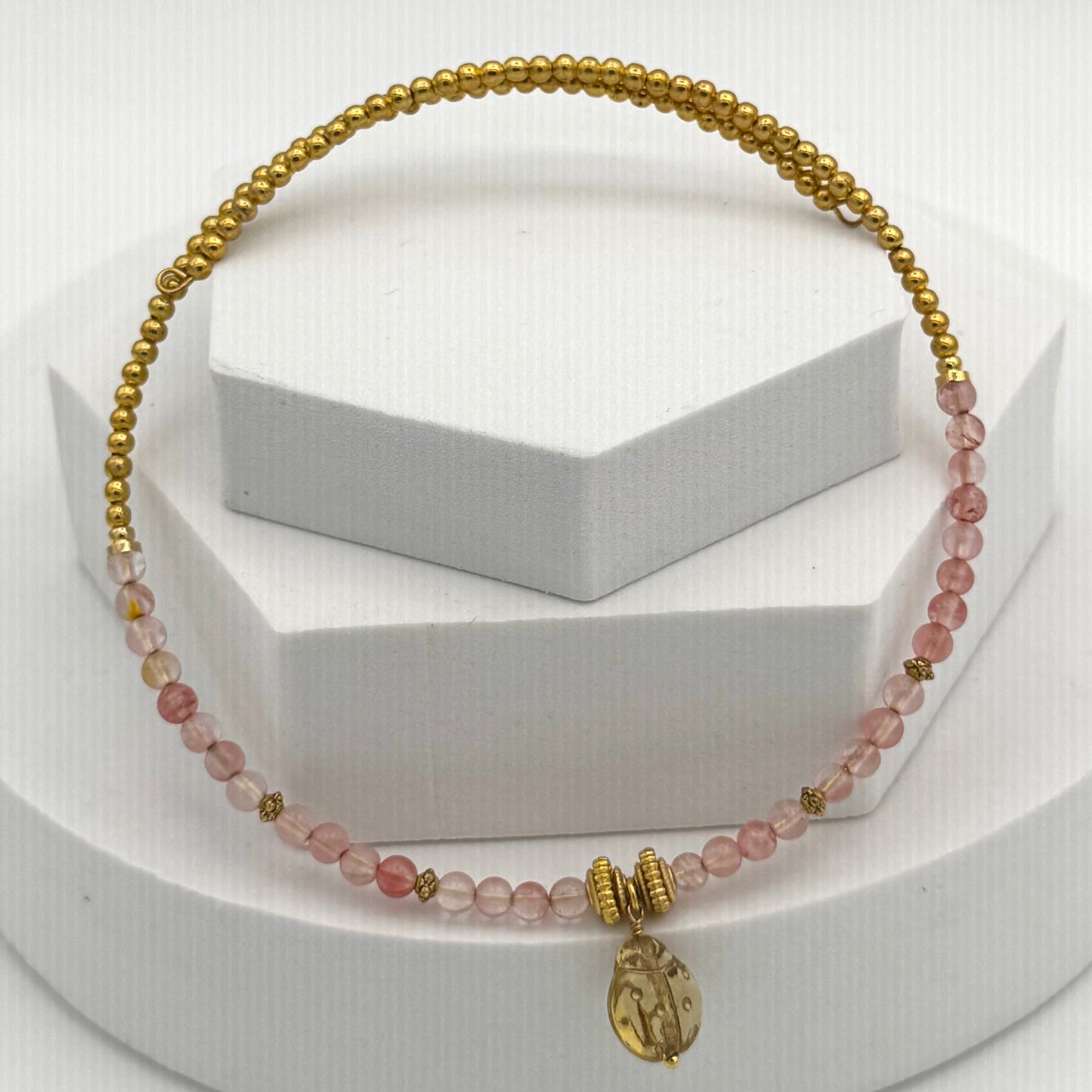 Bracelet with pink beads and gold accents on a white background