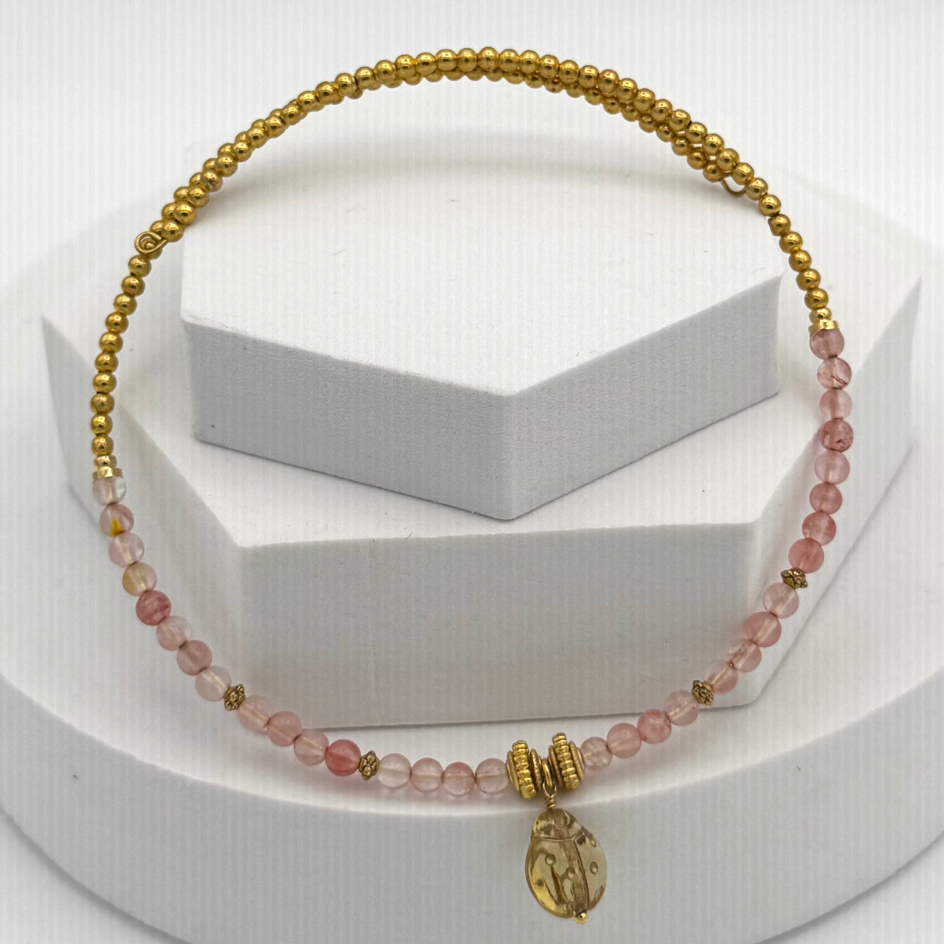Bracelet with pink beads and gold accents on a white background