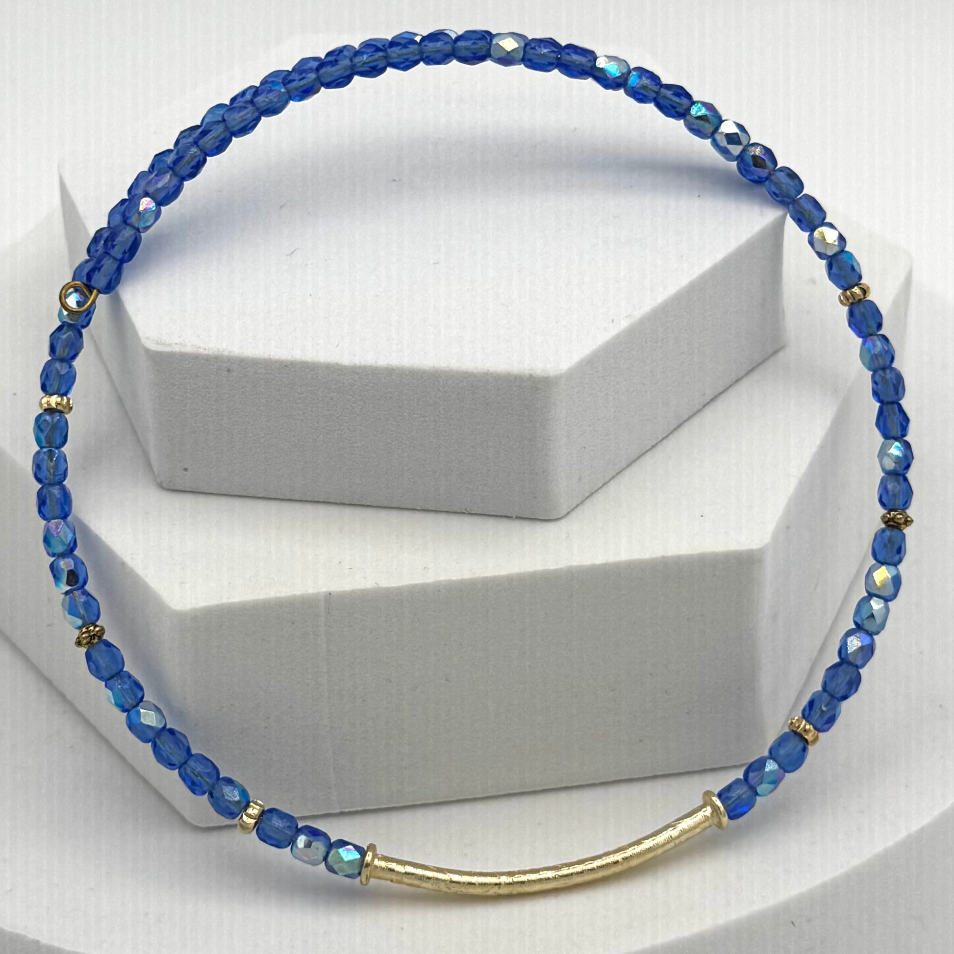 Blue beaded necklace with a gold accent on a white background