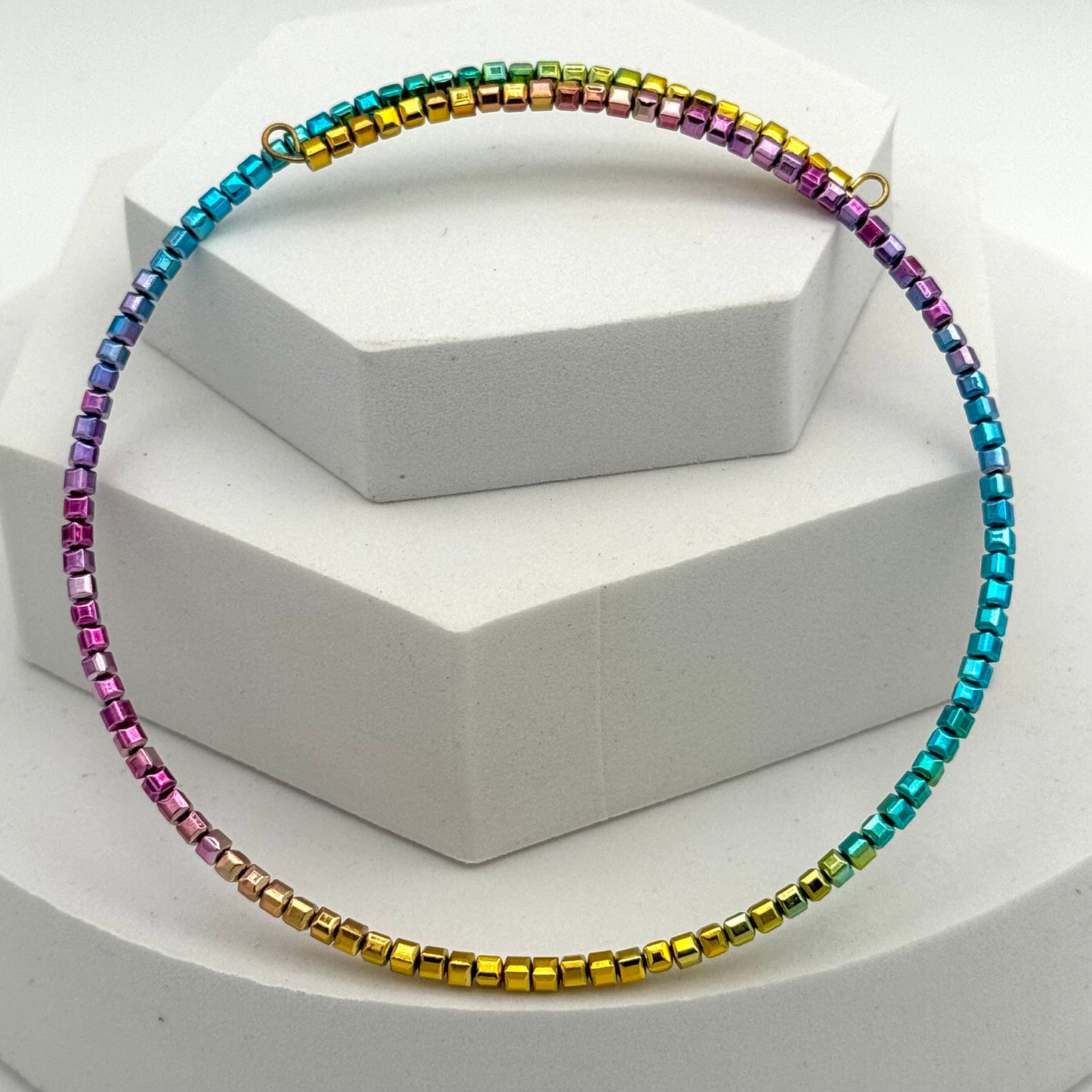 Multicolored beaded necklace on a white hexagonal stand