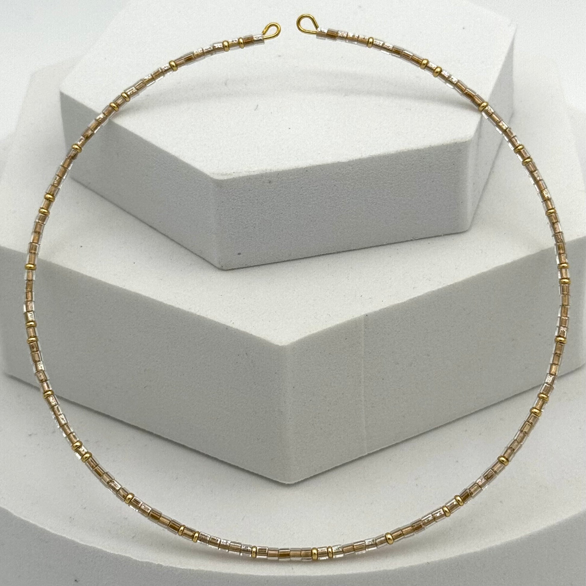 Gold necklace on a white geometric display stand
