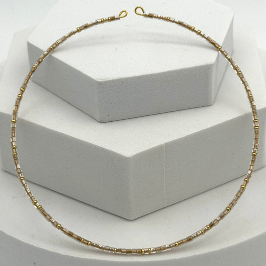 Gold necklace on a white geometric display stand