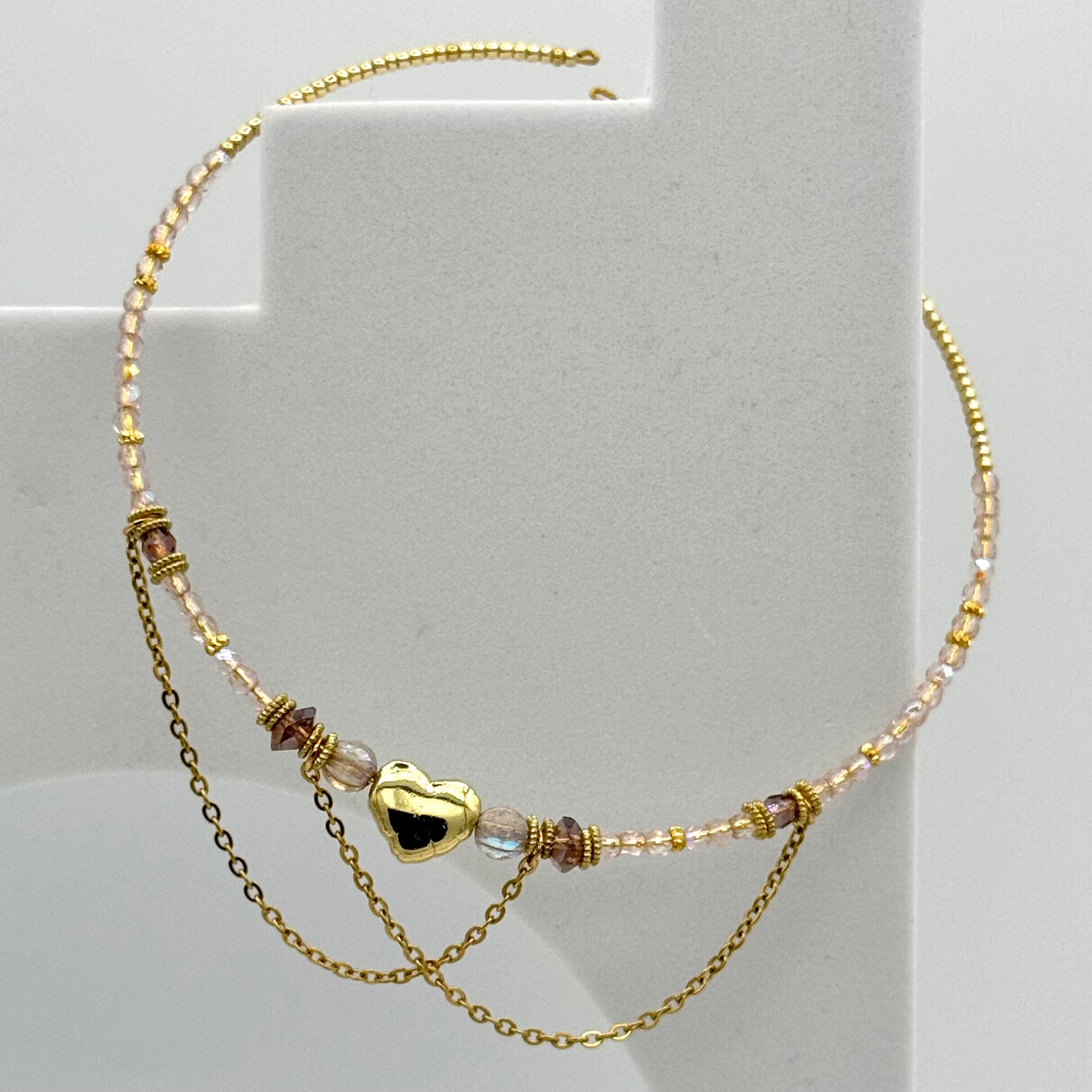 Gold necklace with heart charm on a light gray background