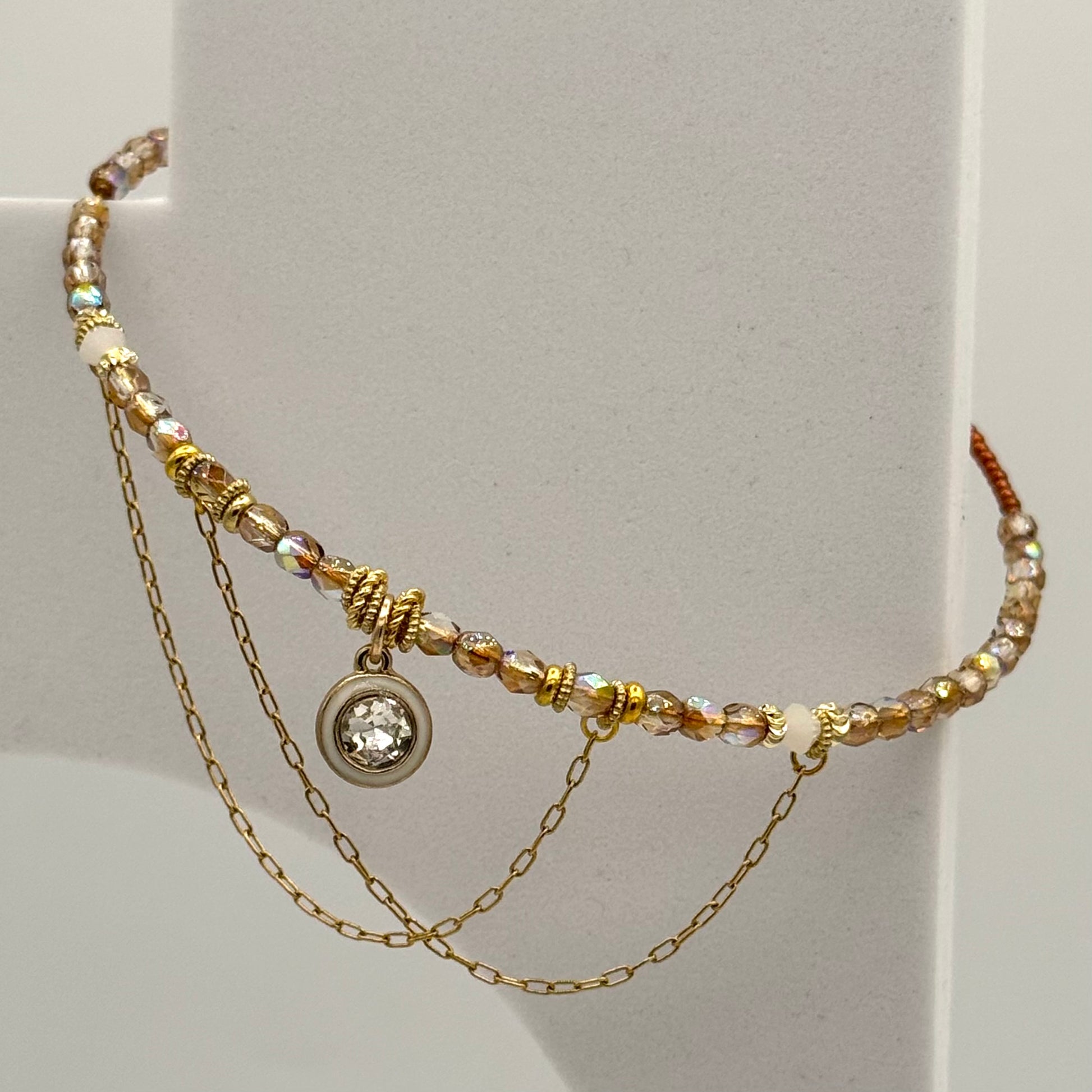 Multistrand beaded necklace with a central pendant on a light gray background
