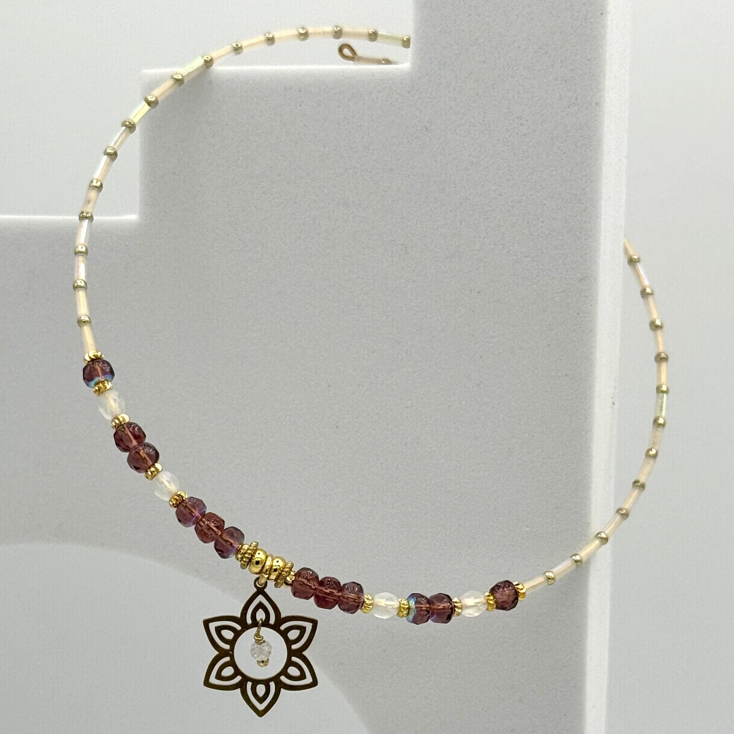 Necklace with beaded chain and decorative pendant on a gray background