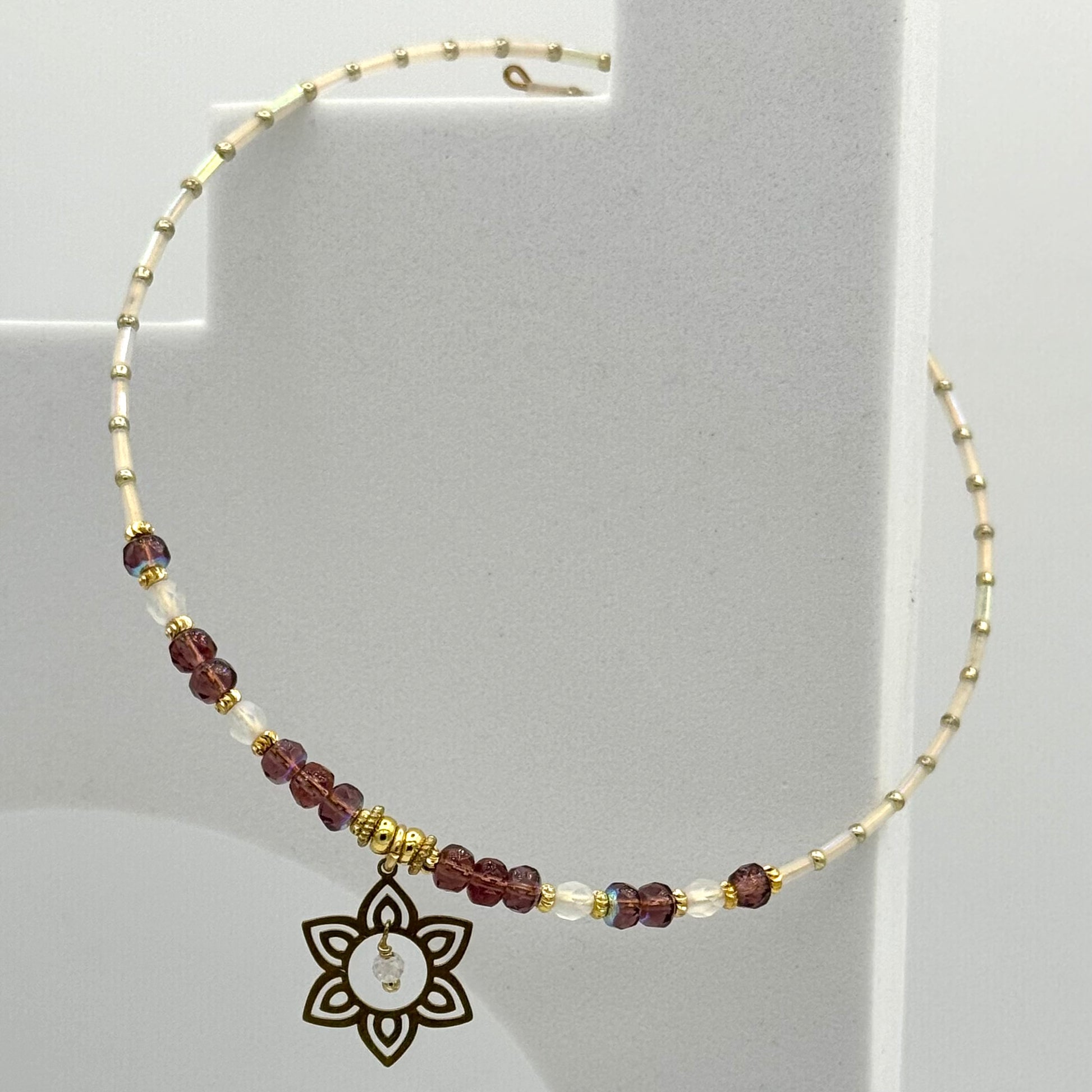 Necklace with beaded chain and decorative pendant on a gray background