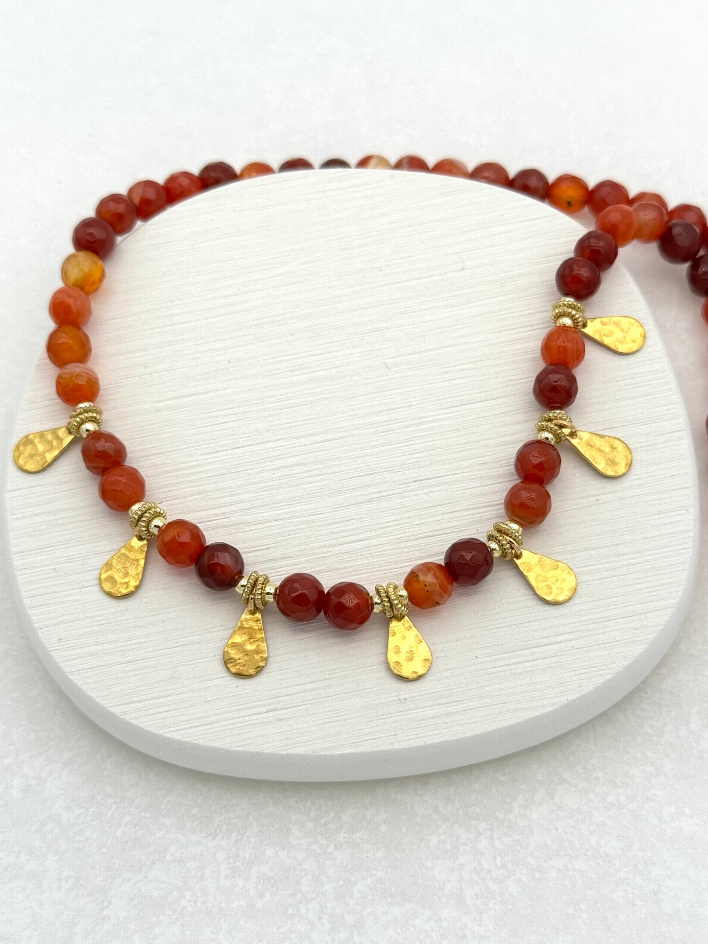 Bracelet with red beads and gold accents on a white surface