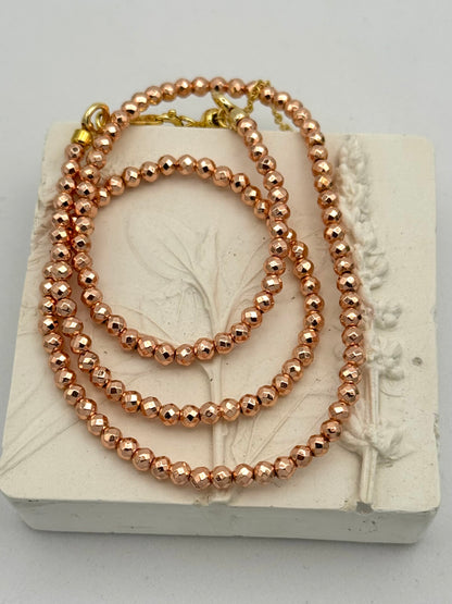Rose gold beaded necklace on a decorative stone block