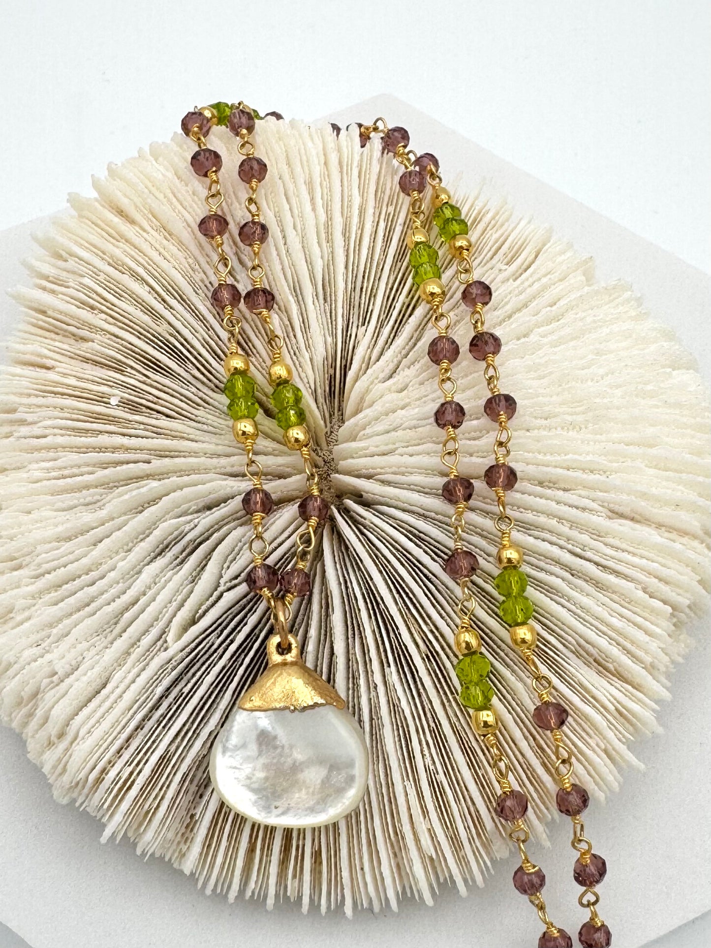 Necklace with beads and a large pendant on a textured white surface
