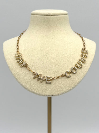 Gold necklace with floral designs on a mannequin bust against a gray background
