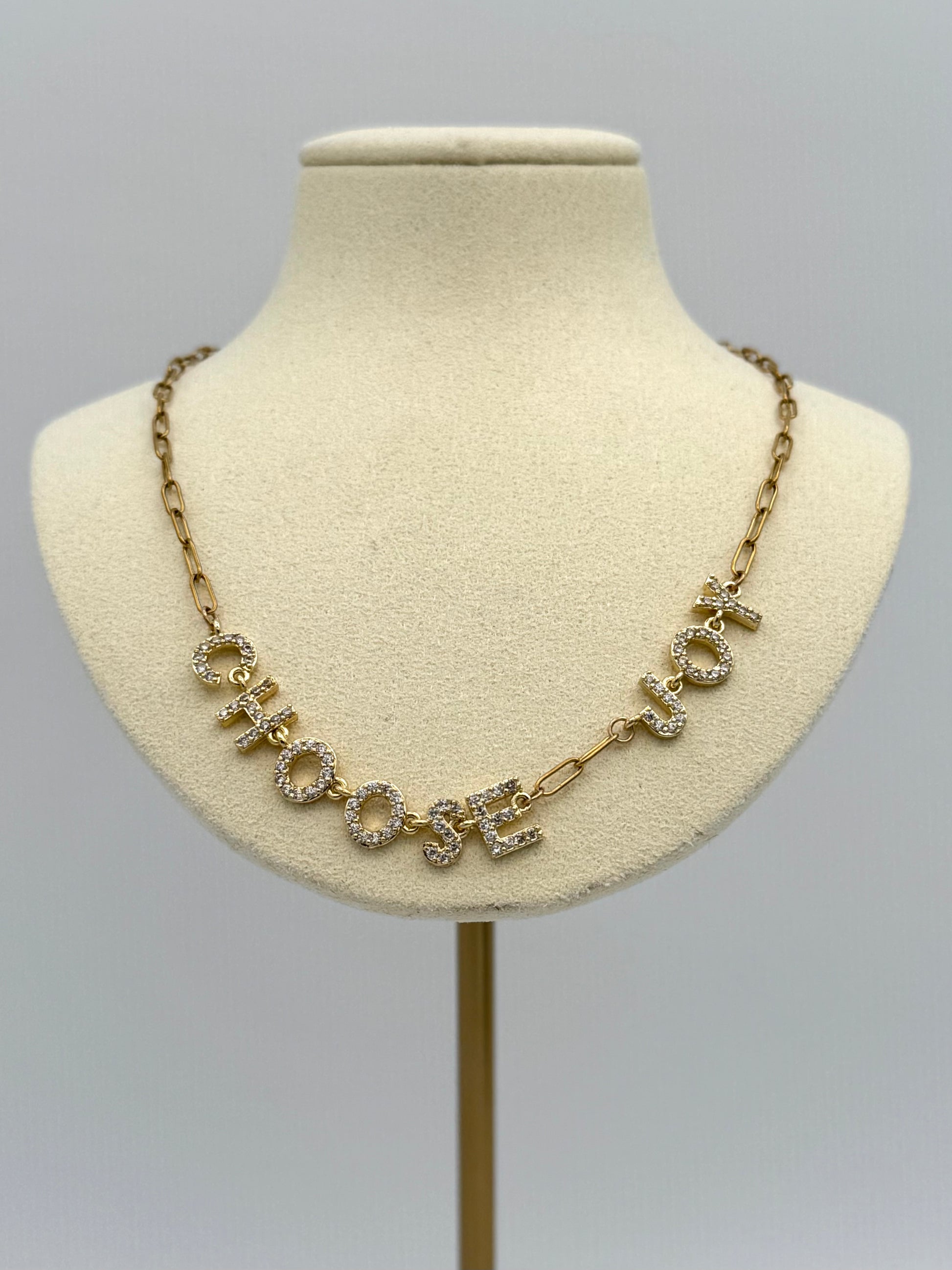 Necklace with 'CHOOSE JOY' on a mannequin bust against a gray background