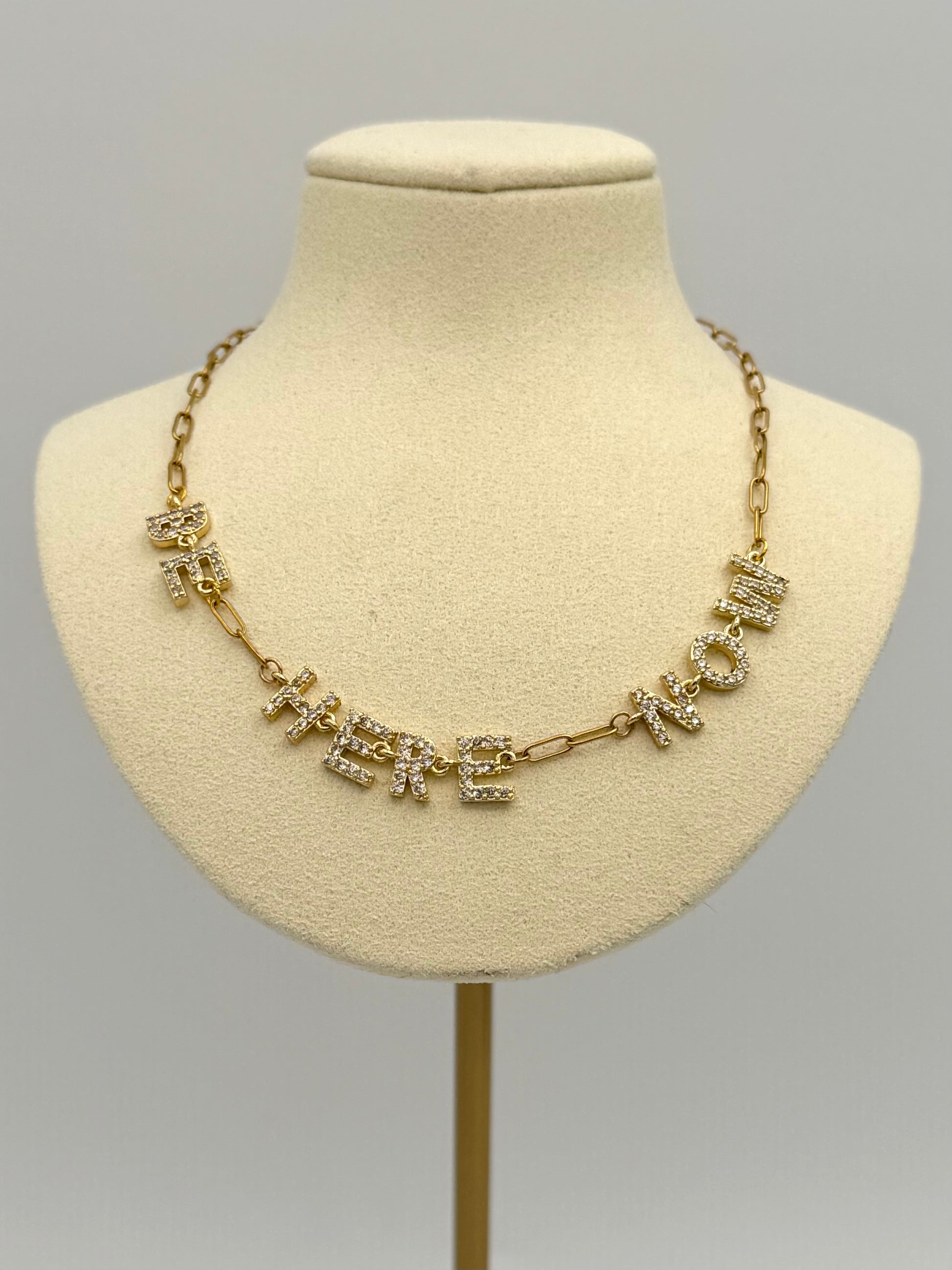 Gold necklace with crystals on a mannequin bust against a gray background