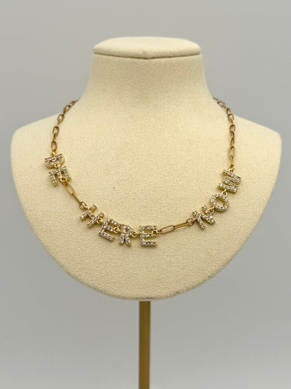 Gold necklace with crystals on a mannequin bust against a gray background