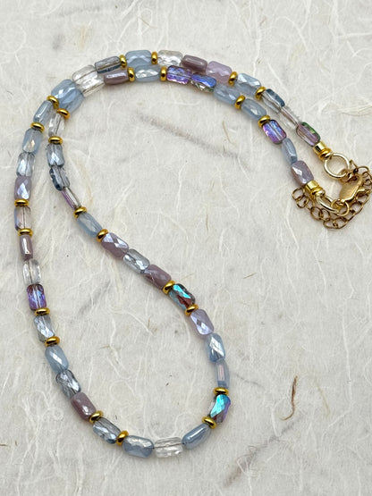 Necklace with multicolored beads and a gold clasp on a textured beige background