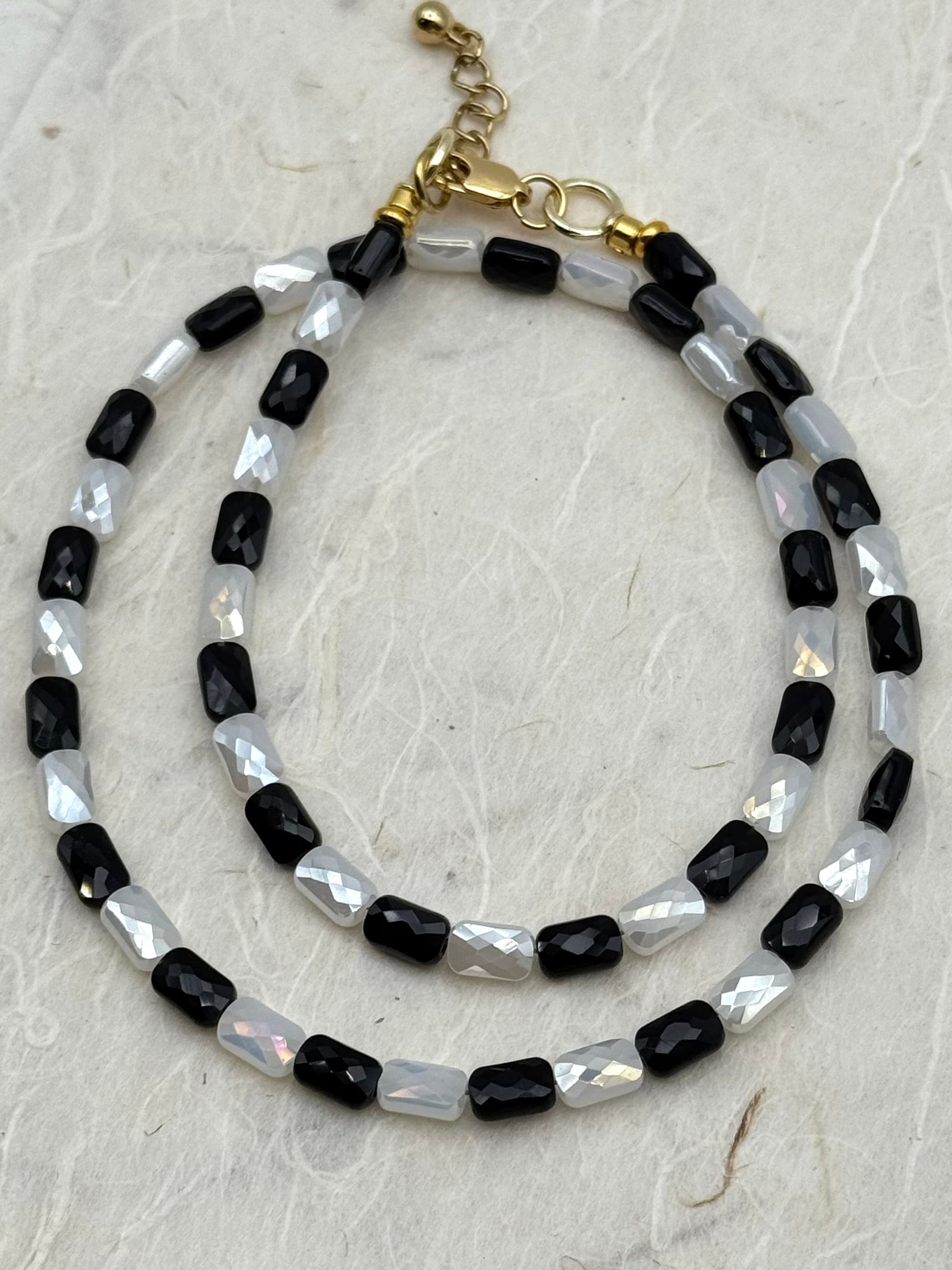 Beaded necklaces with black and white beads on a textured surface