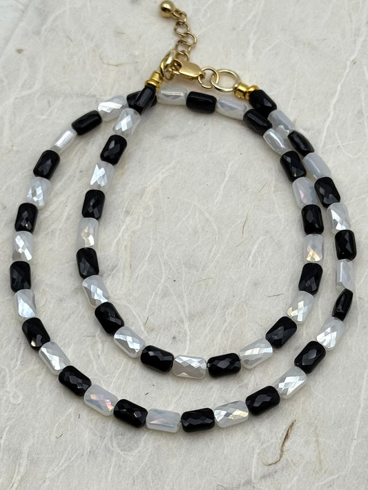 Beaded necklaces with black and white beads on a textured surface