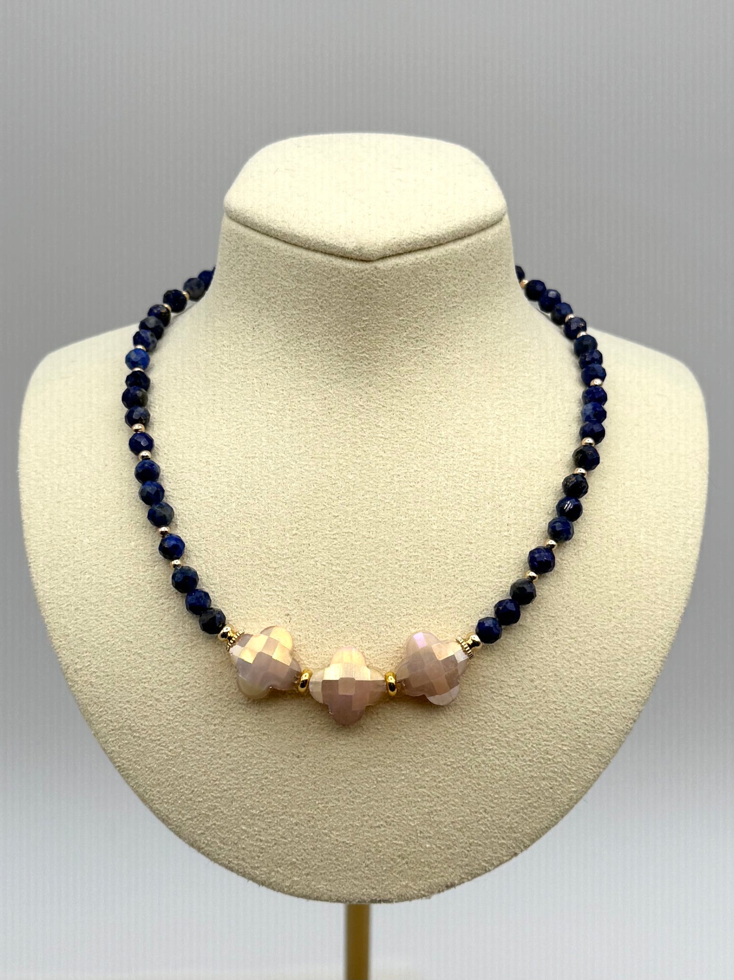 Necklace with dark blue beads and pinkish-beige beads on a mannequin bust against a gray background