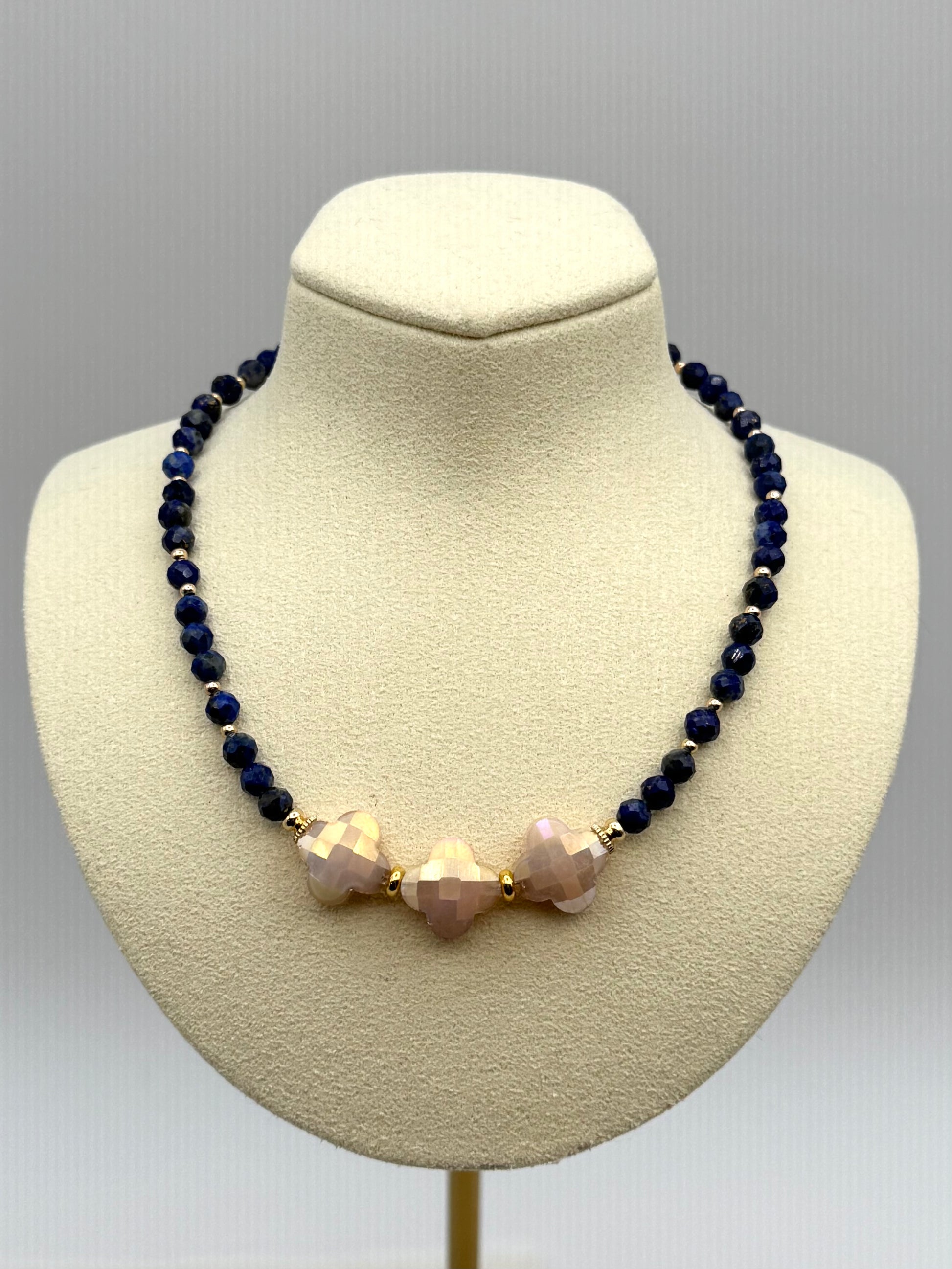 Necklace with dark blue beads and pinkish-beige beads on a mannequin bust against a gray background