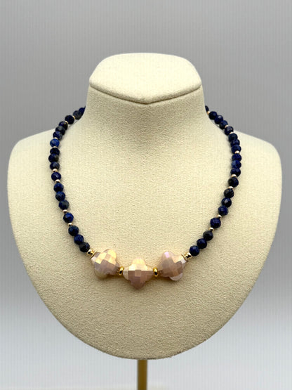 Necklace with dark blue beads and pinkish-beige beads on a mannequin bust against a gray background