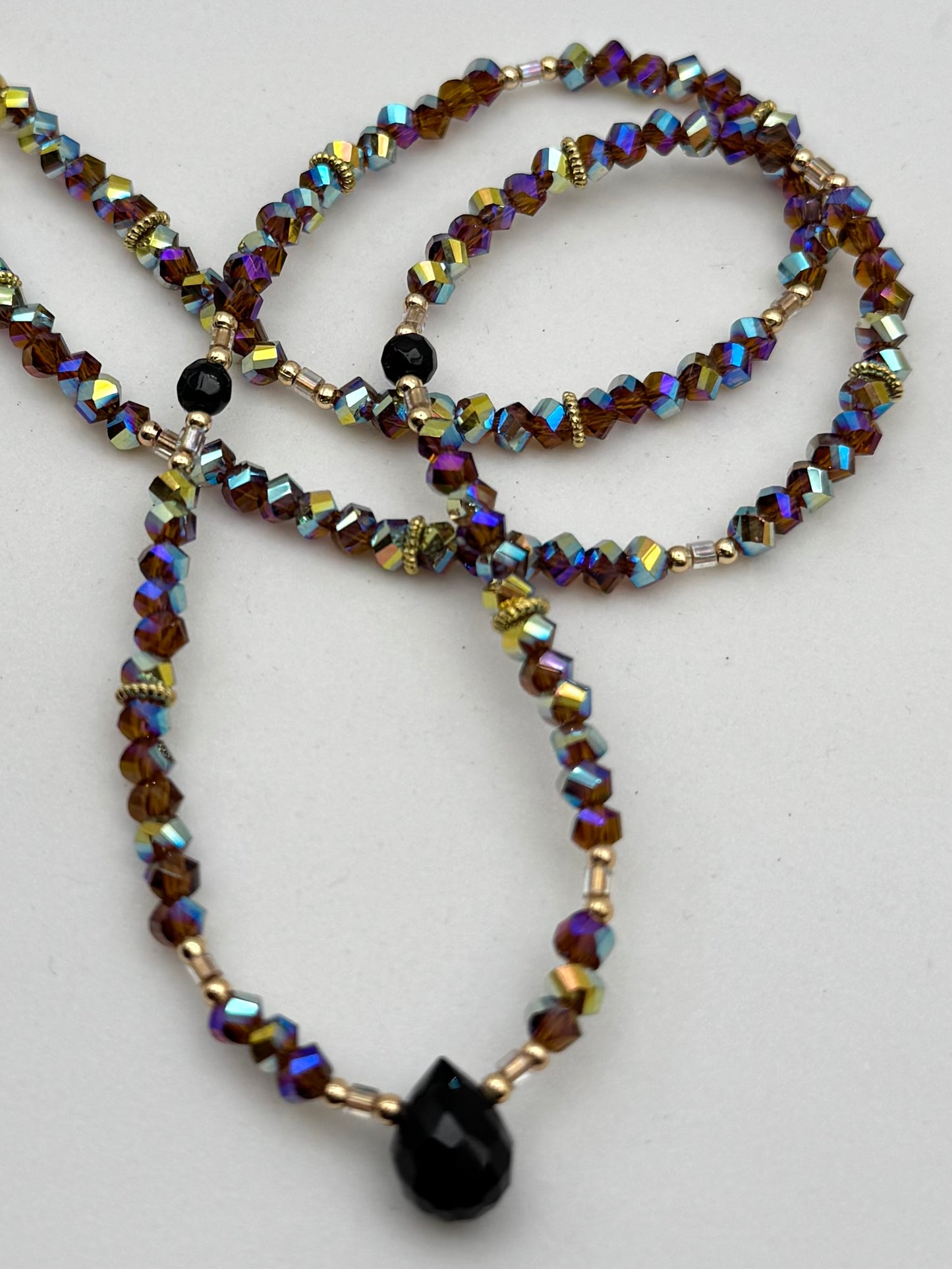 Beaded necklace with multicolored beads and a black pendant on a white background