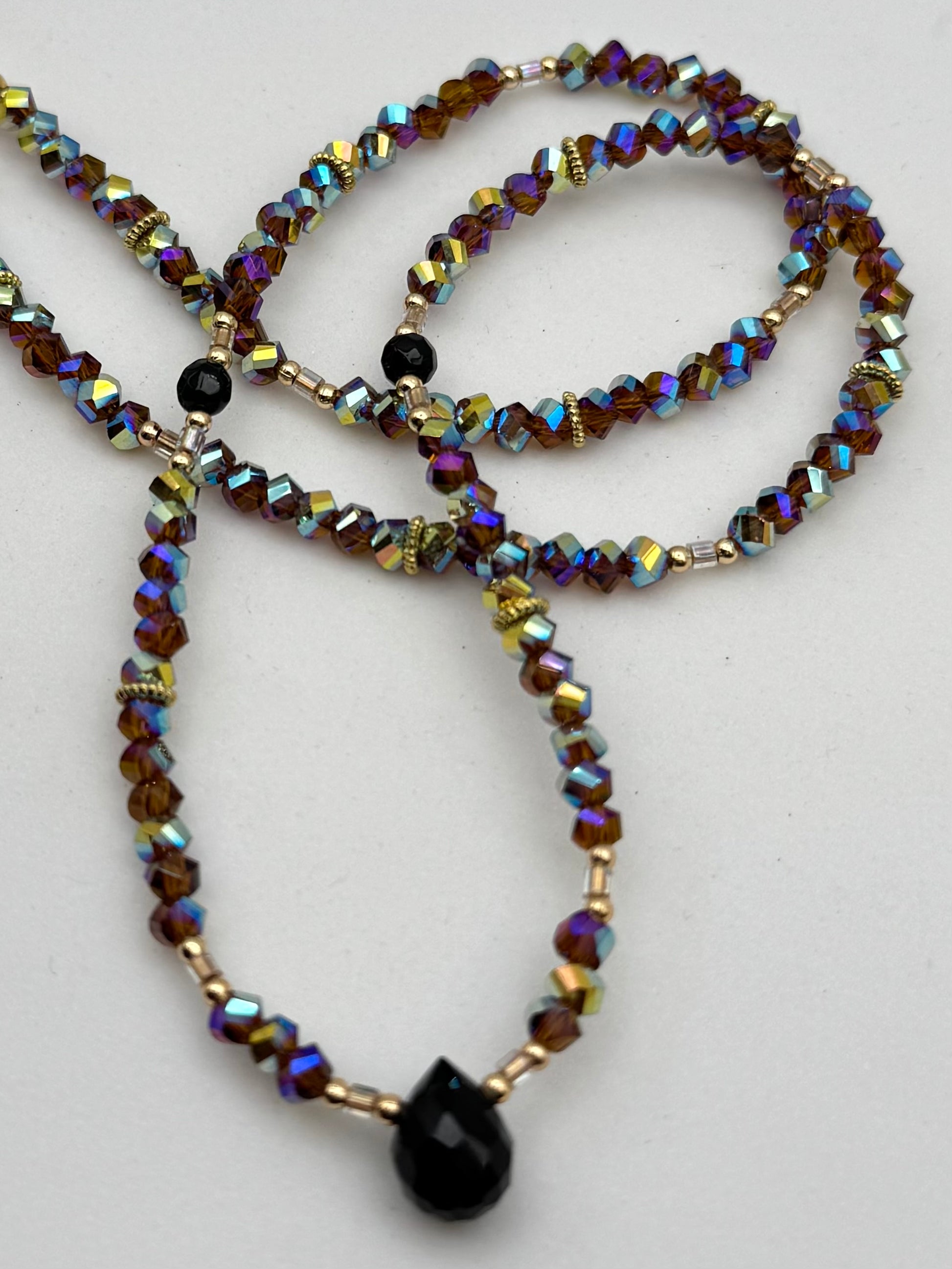 Beaded necklace with multicolored beads and a black pendant on a white background