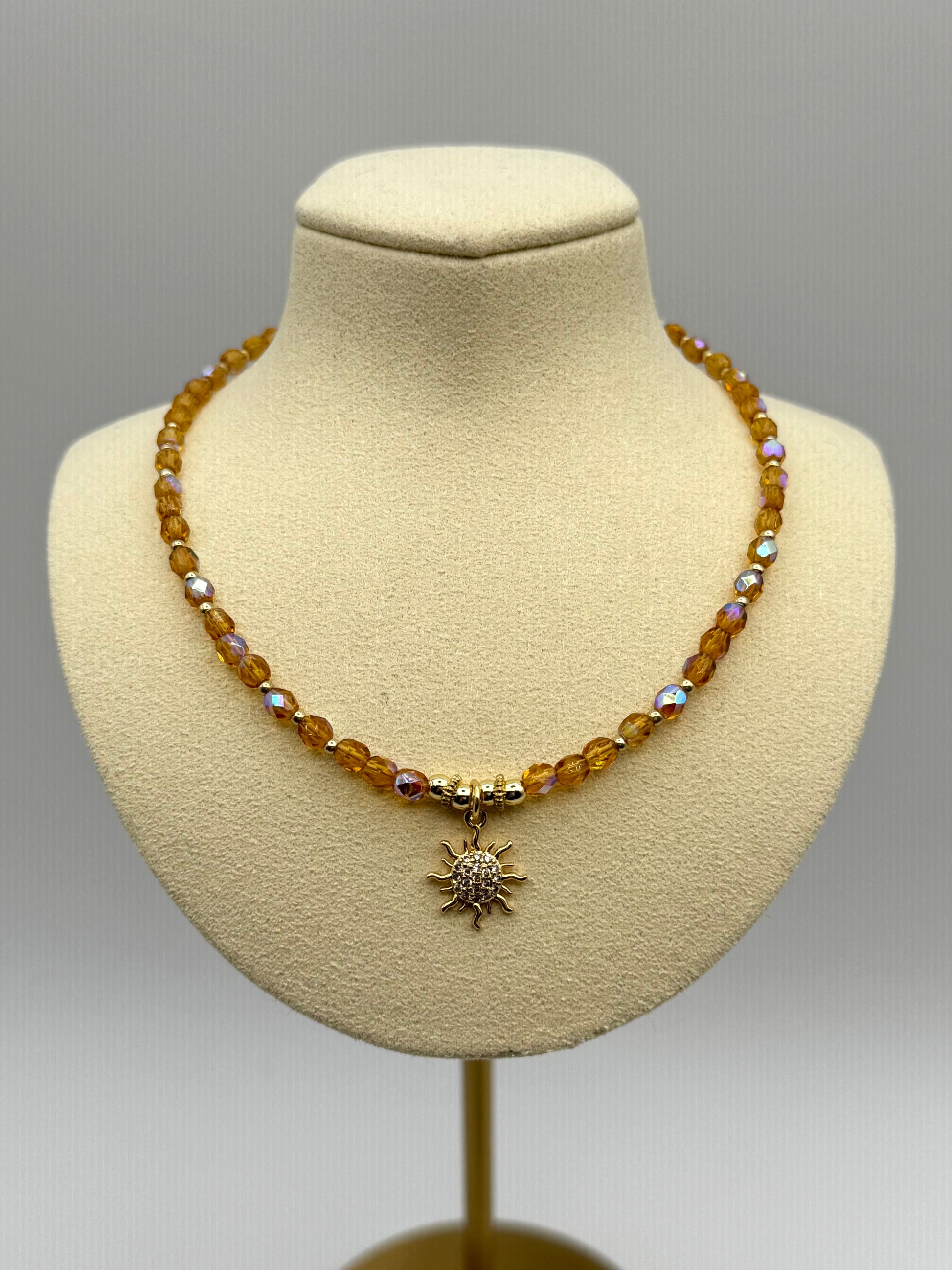 Necklace with a sun pendant on a mannequin bust against a gray background