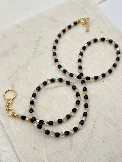 Two beaded necklaces with gold clasps on a textured beige surface