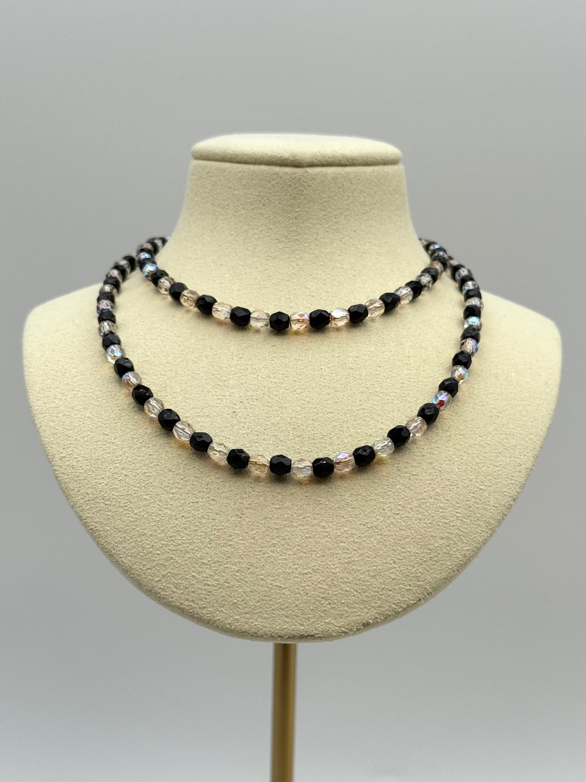 Beaded necklace on a mannequin bust against a plain background