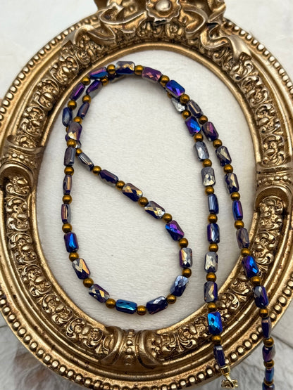 Beaded necklace with blue and gold tones on a decorative gold frame.