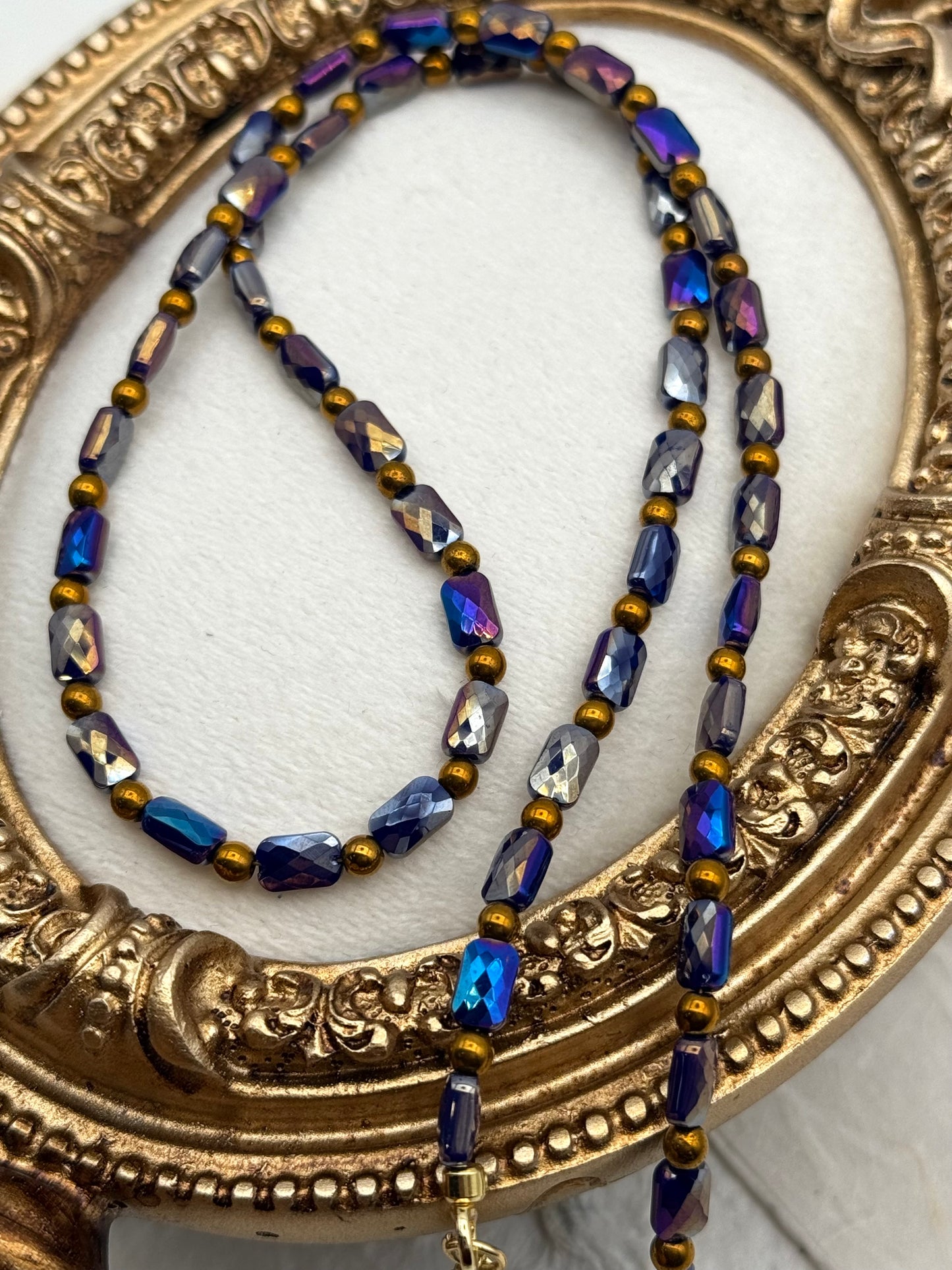 Necklace with blue and gold beads on a decorative gold frame