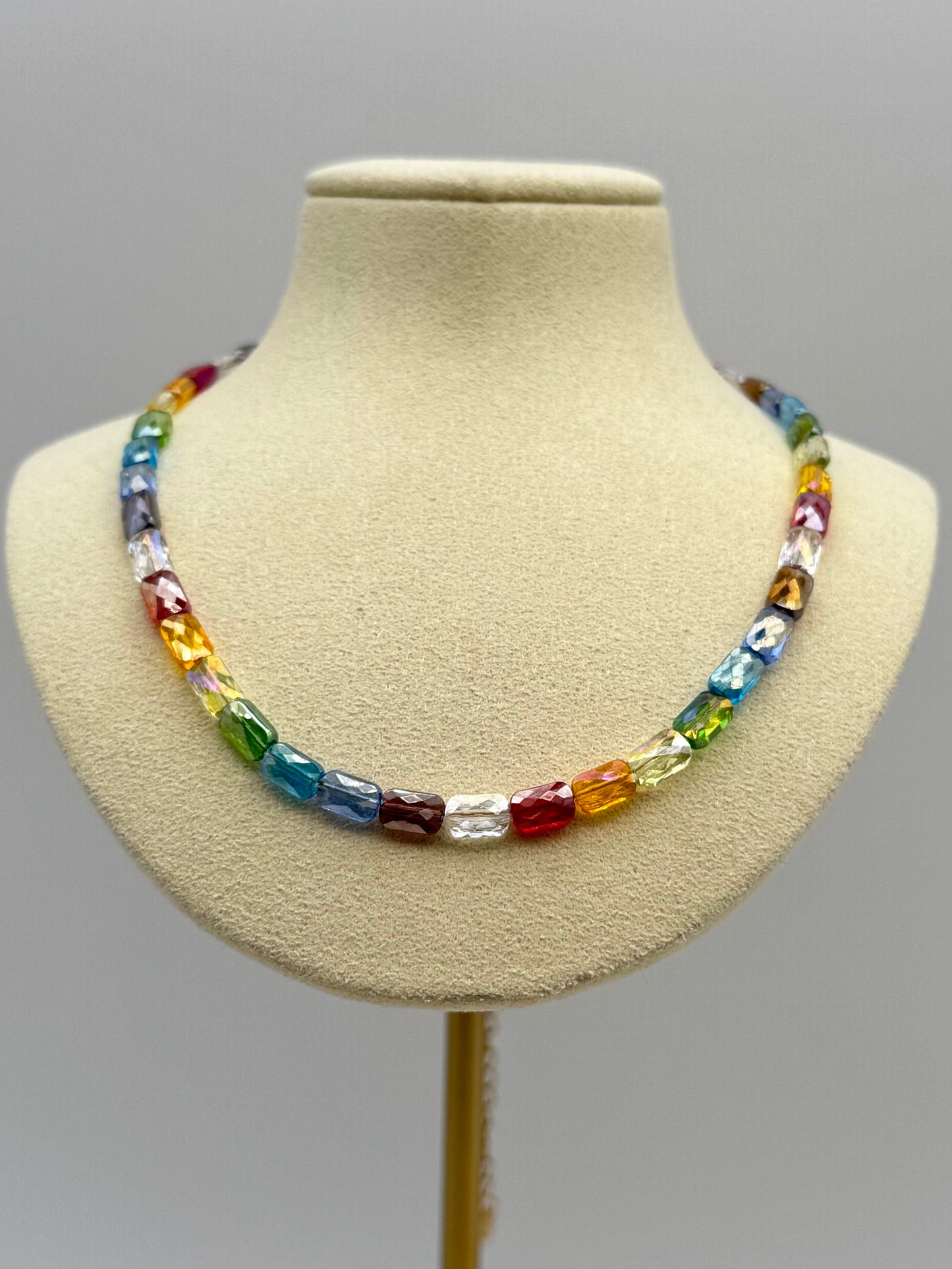 Colorful beaded necklace on a mannequin bust against a gray background