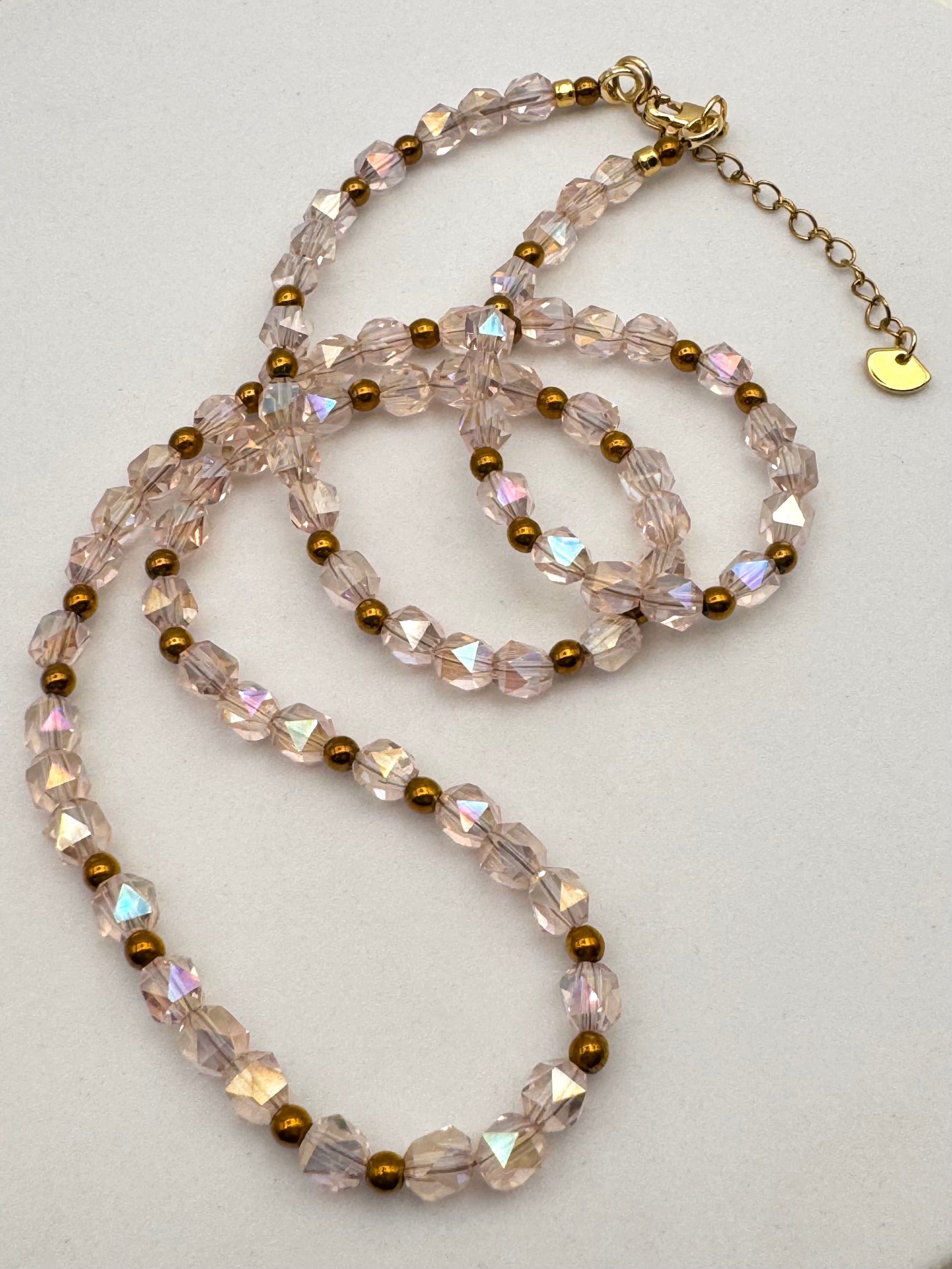 Necklace with clear and gold beads on a light gray background