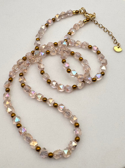 Necklace with clear and gold beads on a light gray background
