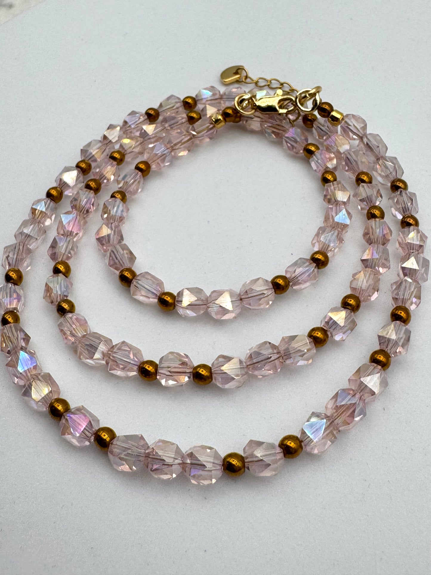 Necklace with pink and gold beads on a light gray background