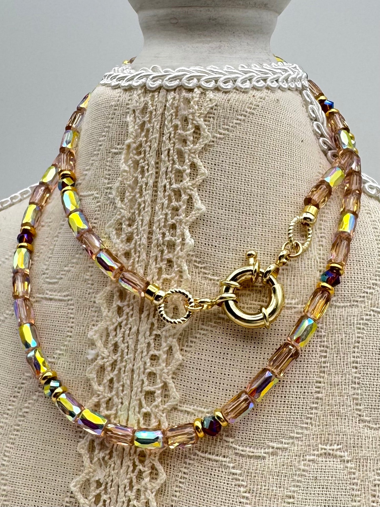 Necklace with multicolored beads and gold clasp on a mannequin with lace background