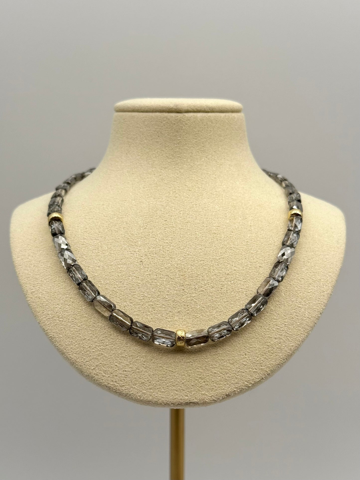 Necklace on a mannequin bust against a plain background