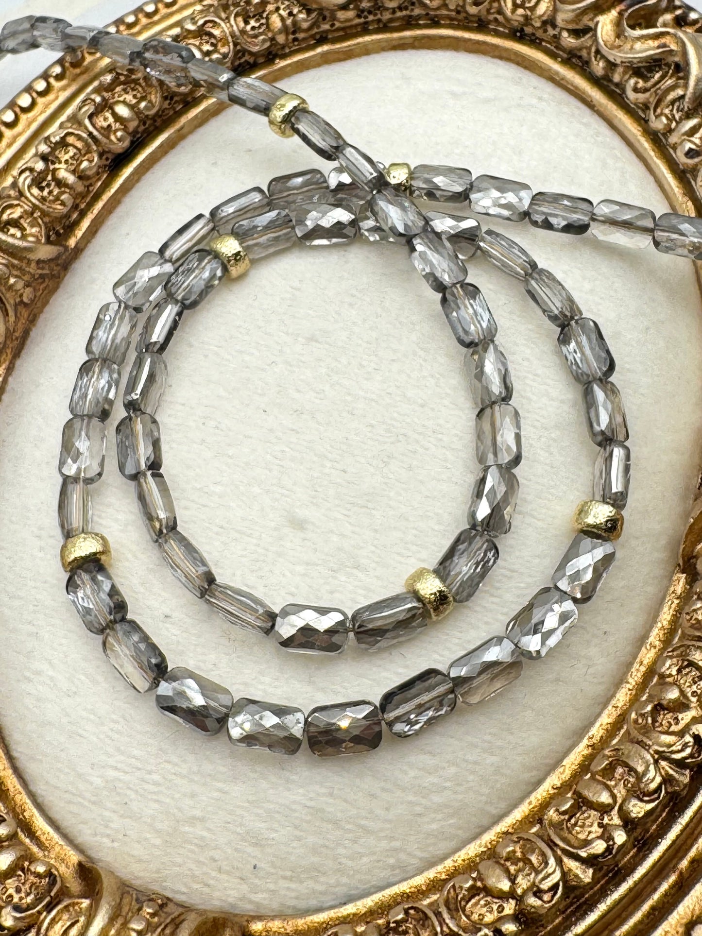 Two beaded necklaces on a decorative gold and white background