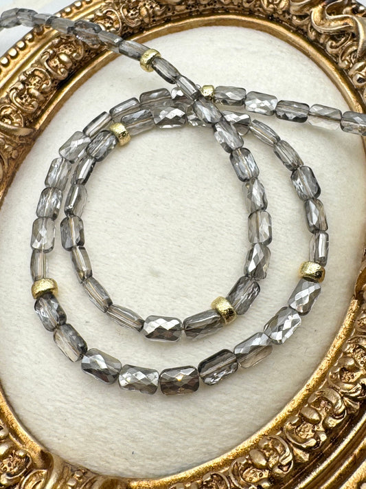 Two beaded necklaces on a decorative gold and white background