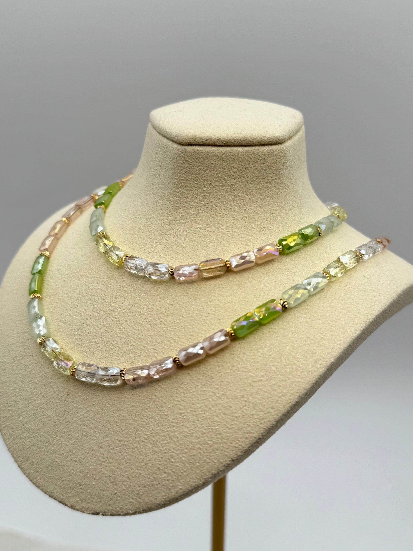 Necklace with multicolored beads on a mannequin bust against a gray background
