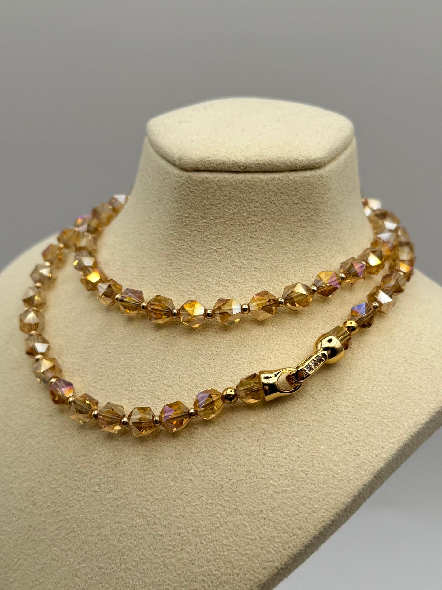 Necklace with brown beaded design on a beige mannequin bust against a gray background