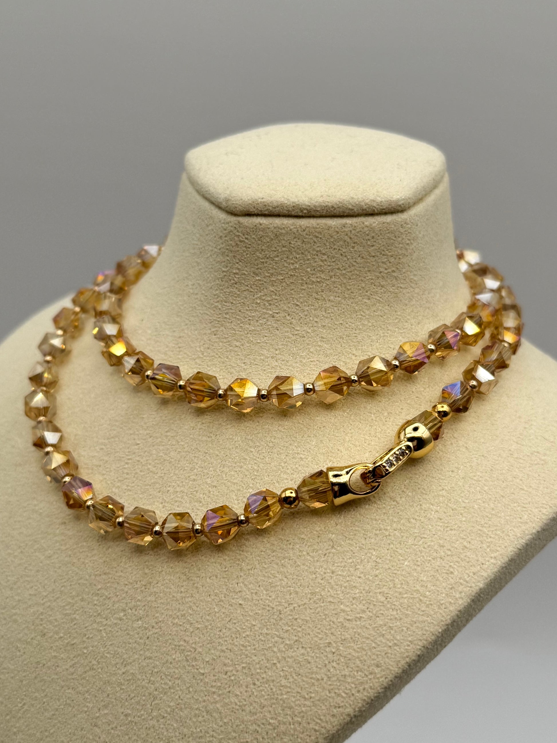 Necklace with brown beaded design on a beige mannequin bust against a gray background