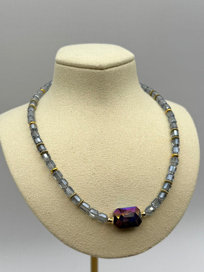 Necklace with a purple gemstone on a mannequin bust against a gray background
