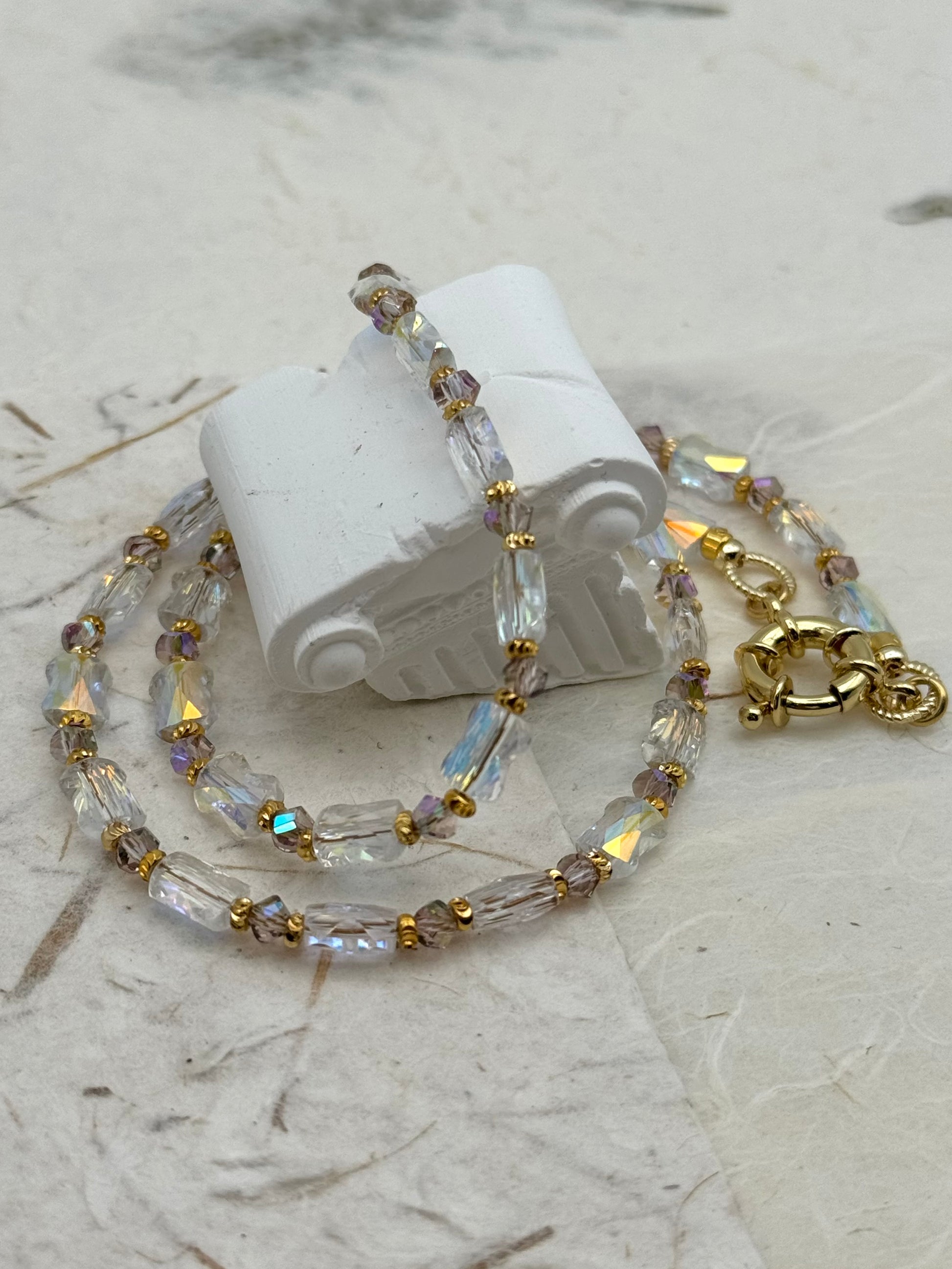 Necklace with clear and gold beads on a marble surface