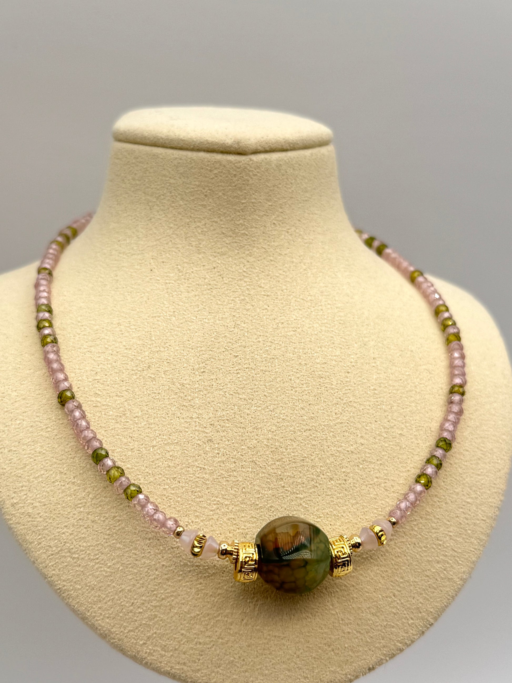 Necklace with multicolored beads on a beige mannequin bust against a gray background