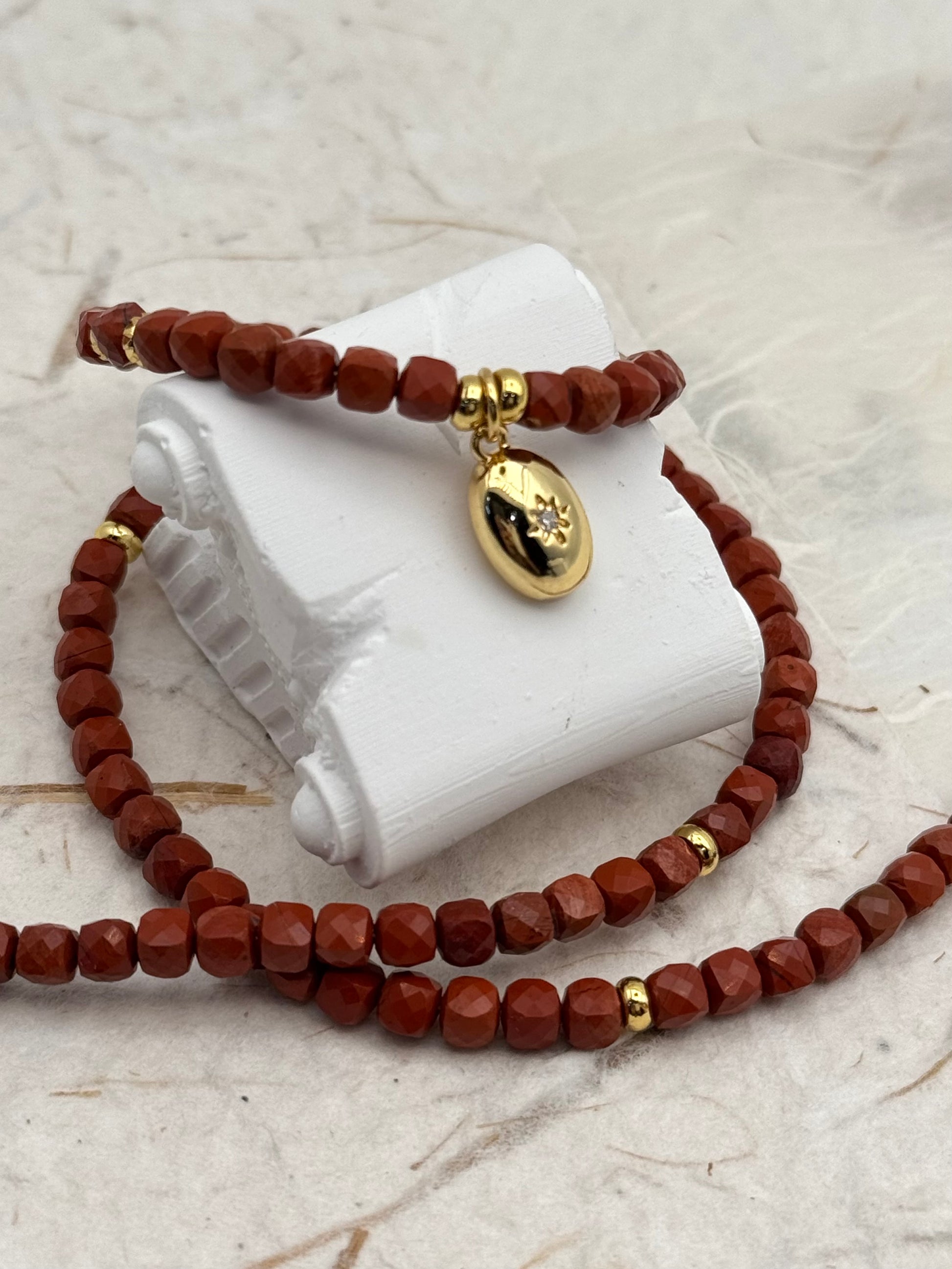Brown beaded bracelet with gold accents on a white stone surface