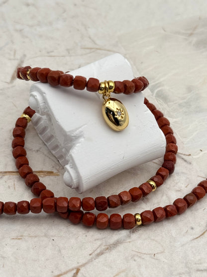 Brown beaded bracelet with gold accents on a white stone surface